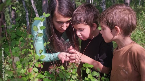 Mother and children observing insects in the forest