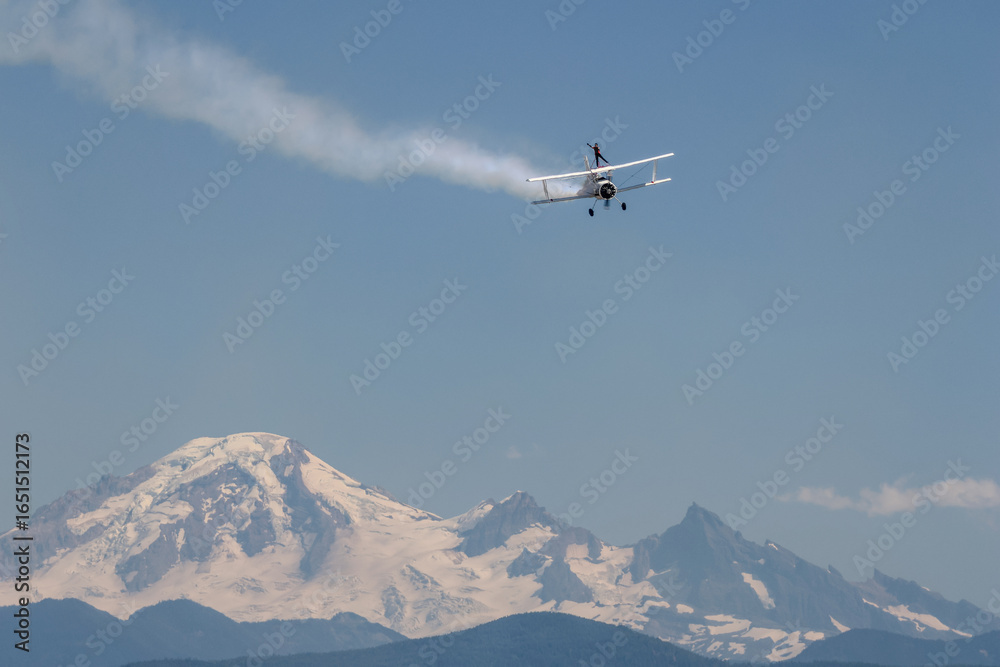 Naklejka premium A person standing in an airplane with a mountain in the background