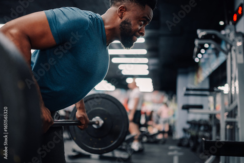 Bild auf Leinwand Determined male athlete lifting weights, achieving fitness goals in gym