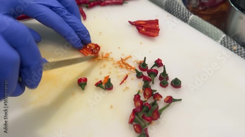 Chopping fresh chili peppers in a kitchen for cooking preparation and flavor enhancement