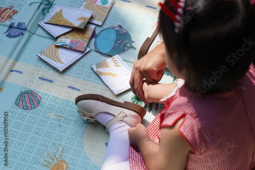 A girl is being taught to put together a puzzle in the shape of the Indonesian national symbol, the Garuda bird