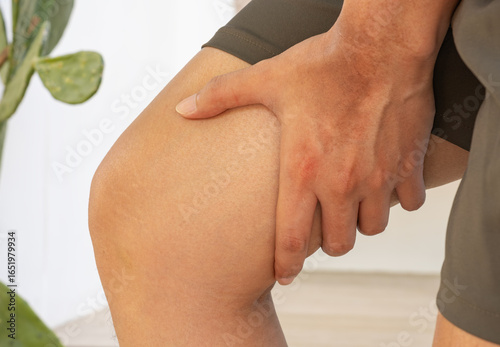 Billede på lærred Close-up of hand gripping thigh—ideal for medical ads on hamstring strain, tendon injury, muscle tension, or joint pain in active, natural recovery environments