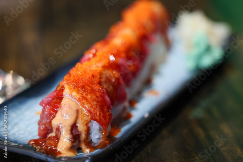Fresh sushi roll at a Japanese restaurant. Raw tuna fish wrapped in seaweed and topped with eggs or seafood roe. 