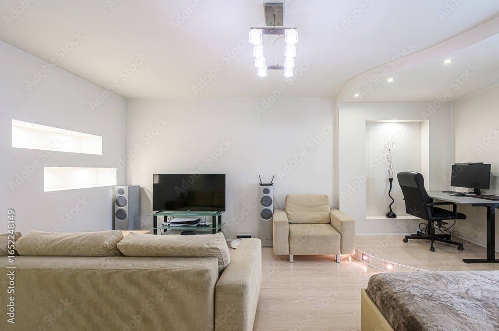 Fototapeta premium bright, modern living room with a sofa, TV, speakers, armchair, and a desk area. White walls and wooden floor create a clean, minimalist space