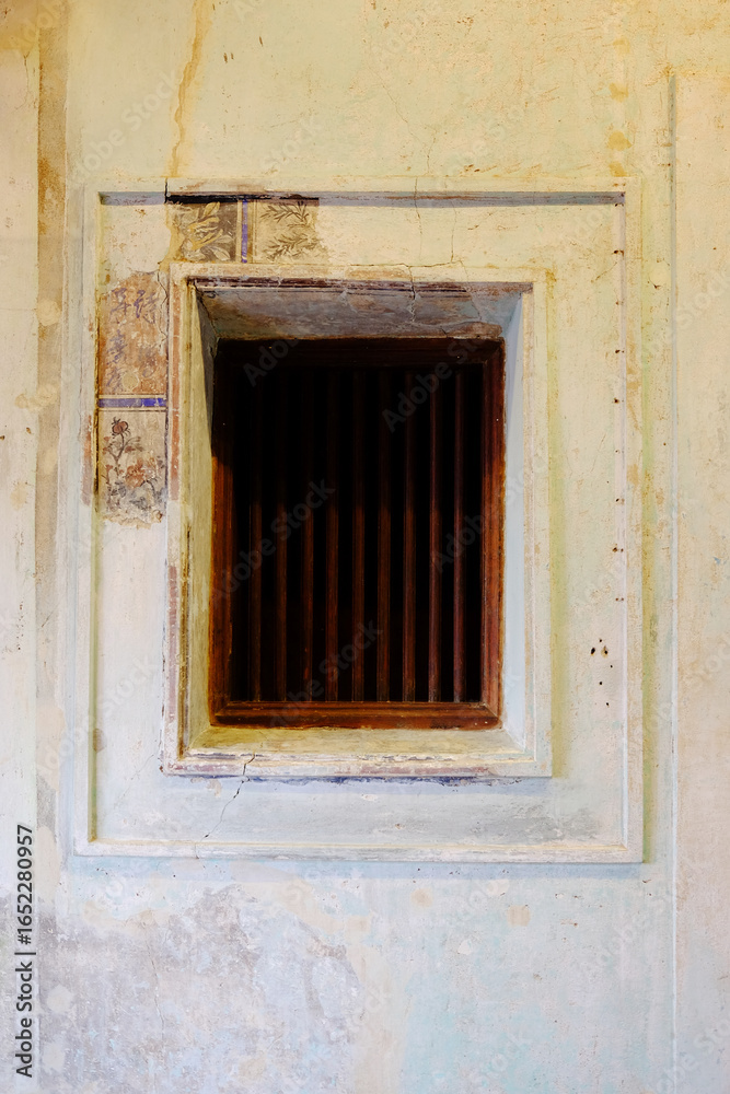 Fototapeta premium Old wrought iron window with ancient painted pattern on vintage and rustic grunge concrete wall interior of Chinese house