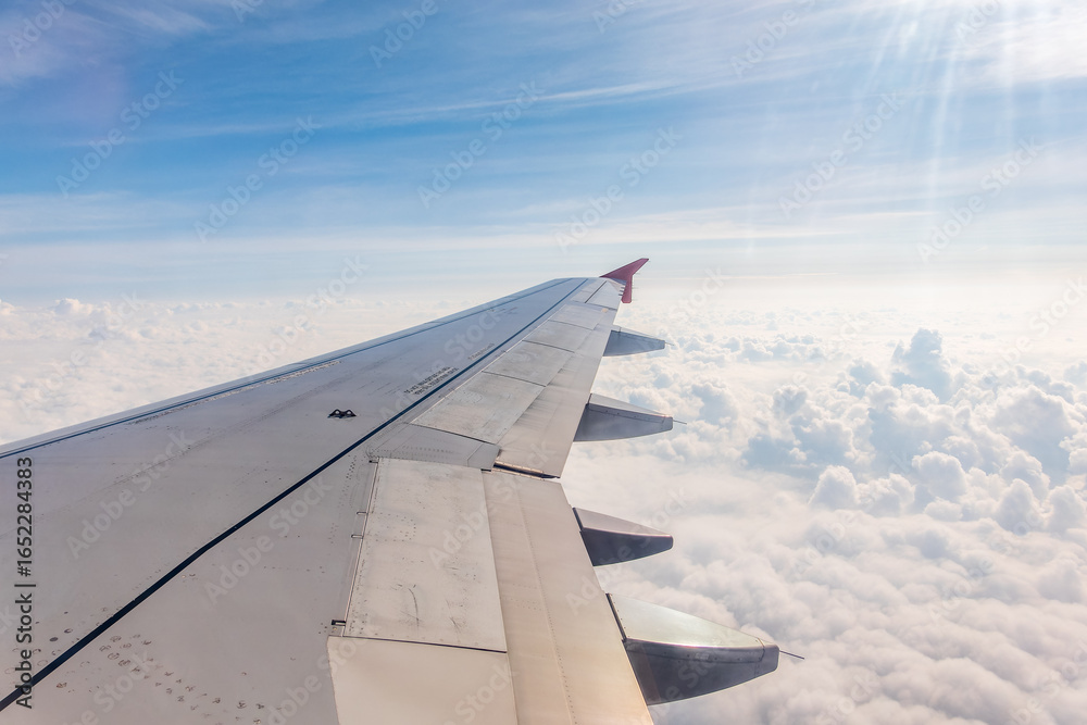 Fototapeta premium View from the airplane window at a beautiful cloudy sky and the airplane wing