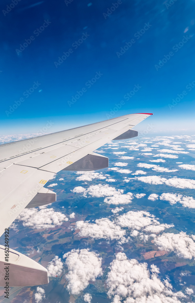 Obraz premium View from the airplane window at a beautiful cloudy sky and the airplane wing