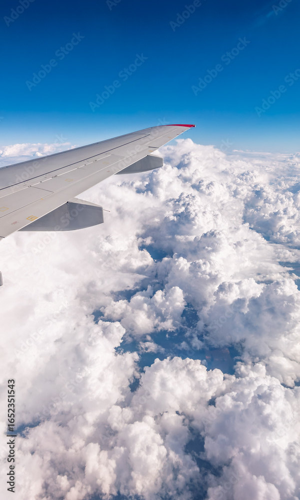 Fototapeta premium View from the airplane window at a beautiful cloudy sky and the airplane wing
