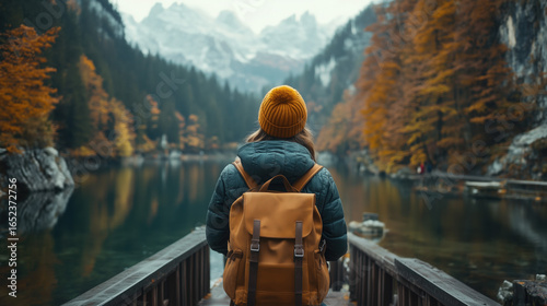 a young traveler with a backpack standing on a bridge overlooking a beautiful lake