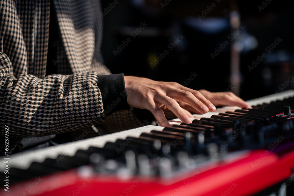 Fototapeta premium Pianist performing live with hands on modern stage keyboard, close-up of keys and fingers, red electronic piano detail symbolizing creativity, sound, art, melody, music performance and inspiration