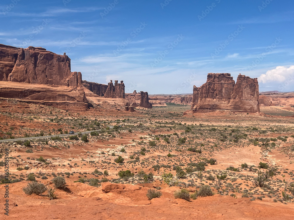 Fototapeta premium Wide desert landscape with multiple red rock formations including the Three Sisters in Arches National Park.