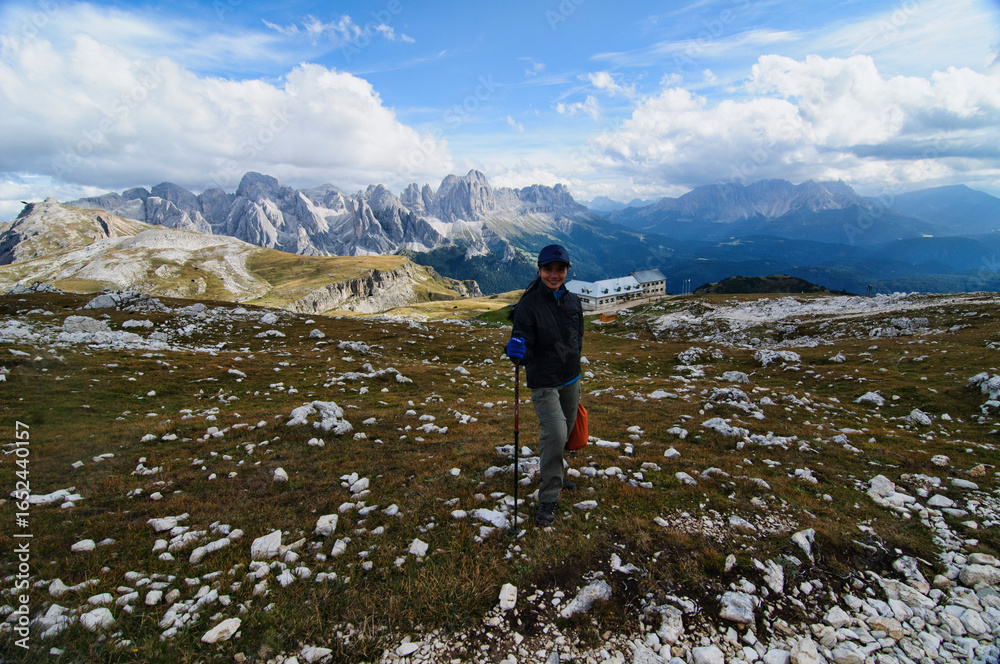 Obraz premium A trekker enjoying the beautiful view of Bolzano in the Catinaccio in the Dolomites, Italy