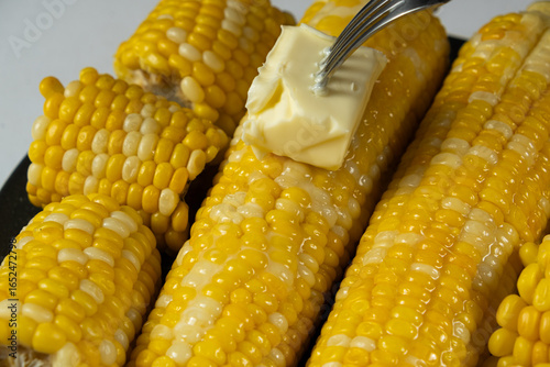 Принти на полотні Hot Corn Cobs Covered with Creamy Butter Spread.