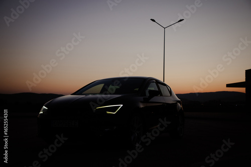 A modern black sport car in the sunset