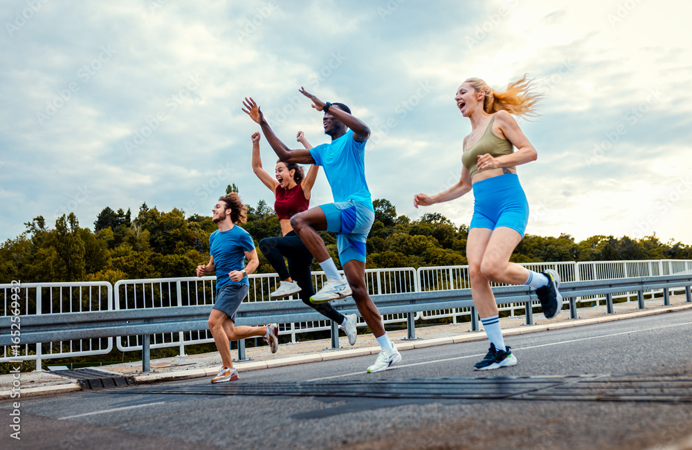 Obraz premium Excited group of people running and jumping together on outdoor road.