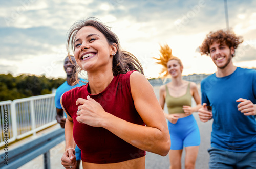 Smiling group of people running together on outdoor road.