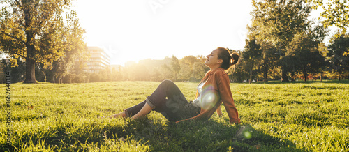 Peaceful woman relaxing on green grass with meadow in background