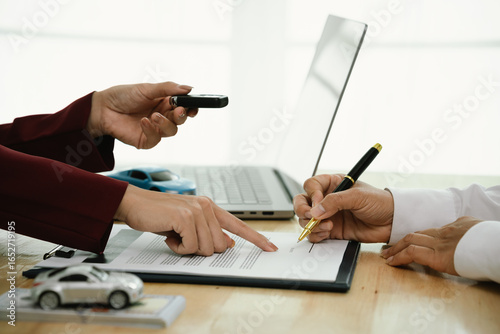 A businessman and client complete an agreement by signing documents for car insurance, loan, or rental, symbolizing finance, contract, policy, investment, purchase, legal paperwork, and secure ownersh