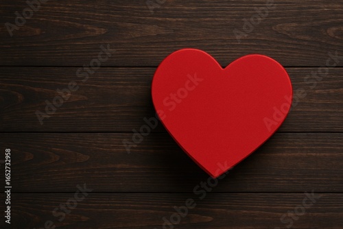 Top-down view of a red heart-shaped gift box for Valentine's Day on a dark wooden table