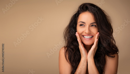 Fotografie Happy beautiful millennial brunette half-naked woman with gorgeous long hair and glowing skin looking at copy space and smiling, isolated on beige background