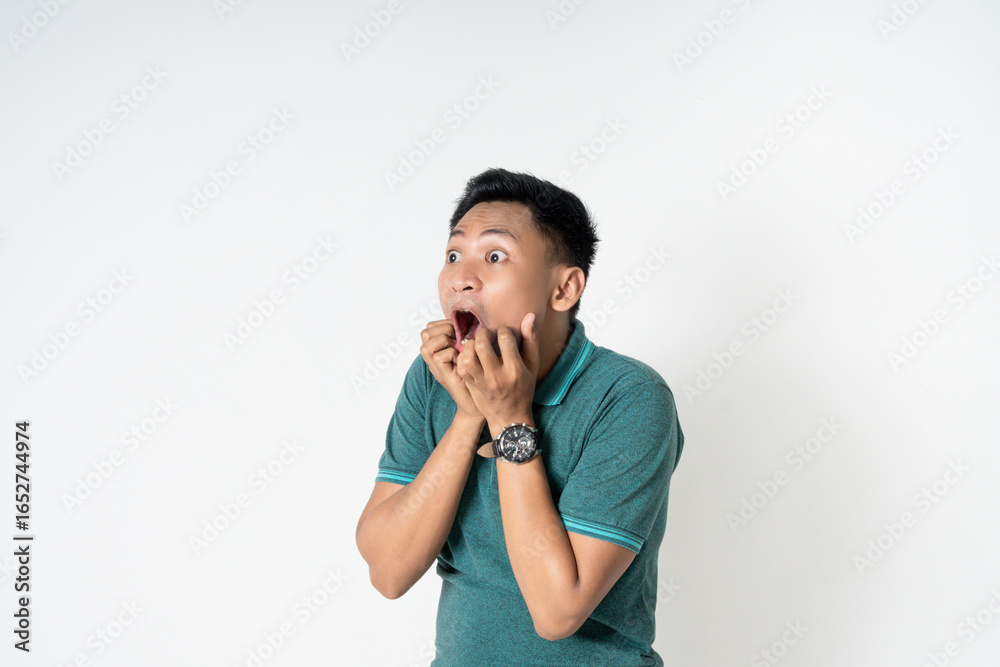 Asian young man wearing a green shirt looks surprised and shocked, isolated over whited background Asian young man wearing a green shirt looks surprised and shocked, isolated over whited background