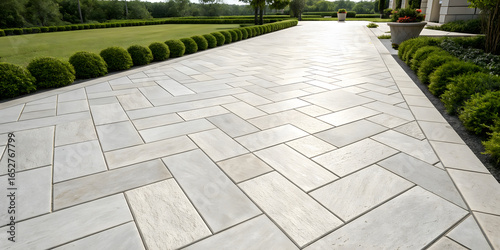Beige natural stone paving in formal garden setting with herringbone pattern surrounded by manicured hedges and landscaping elements.