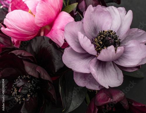 Close-up of a bouquet of vibrant peonies and anemones in shades of pink, purple, and dark burgundy