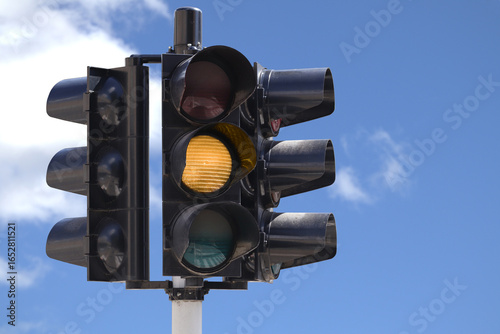 Yellow traffic light with the blue sky as background.