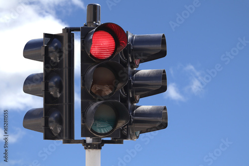 Traffic light with the red light on with the sky as background.