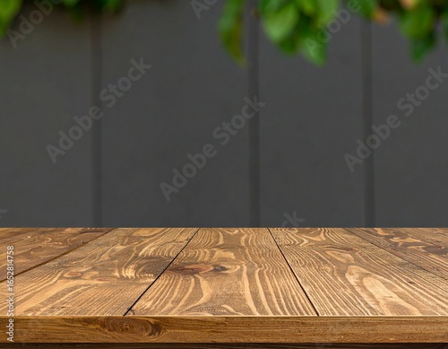 Wooden tabletop against a blurred gray wall with greenery