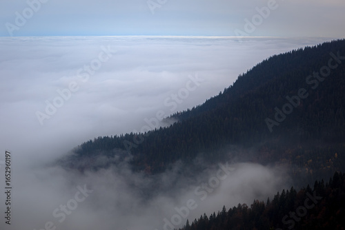 An aerial view of stunning mountains enveloped in clouds near Kopaonik, Serbia, showcasing natural beauty and tranquility.