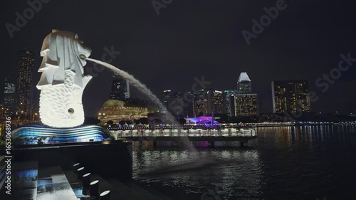 The stunning Merlion statue in Singapore, illuminated against the night skyline. Water flows from its mouth, creating a mesmerizing spectacle. A symbol of the city, this blend of tradition and moderni