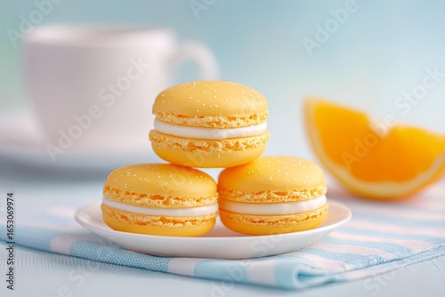 Delicious yellow macarons with fresh orange slices on a plate.