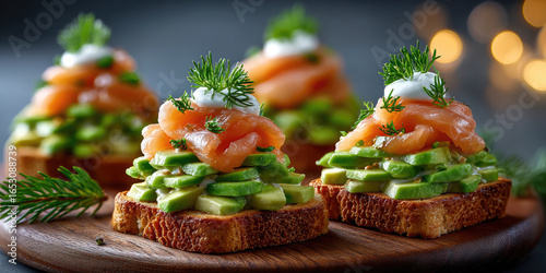 Christmas-themed appetizers on a wooden platter. Toasts topped with avocado, smoked salmon, and cream, garnished with dill. Soft bokeh lights in the background.