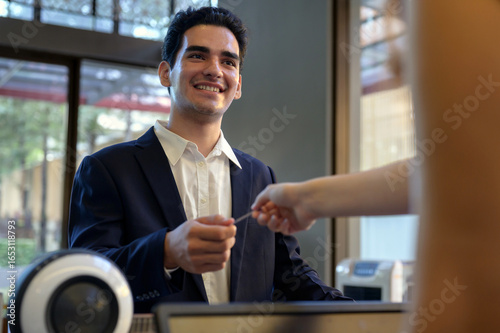 Guest takes room key card during check-in process at the hotel counter. Business travelling guest receiving room access.