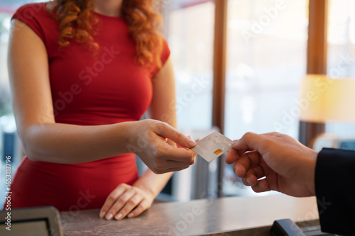 Close-up customer hand while paying for services at hotel. Female guest using a credit card for payment. service hotel and payment concept.