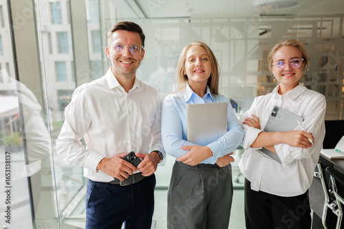 Team of professionals confidently collaborating in a modern office setting with innovative technology and bright smiles