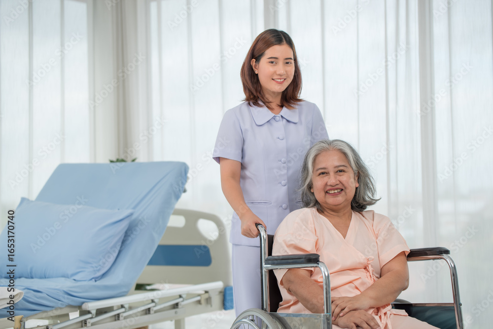 Fototapeta premium Asian nurse pushing senior female patient in a wheelchair at the hospital ward