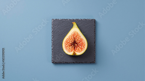 Fresh Cut Fig Half on Slate Board Against Blue Background for Food Photography and Culinary Design