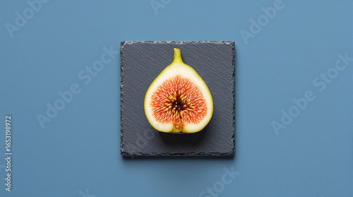 Fresh Ripe Fig Halves Arranged on Black Slate Board with Blue Background for Healthy Food and Nutrition Culinary Concepts