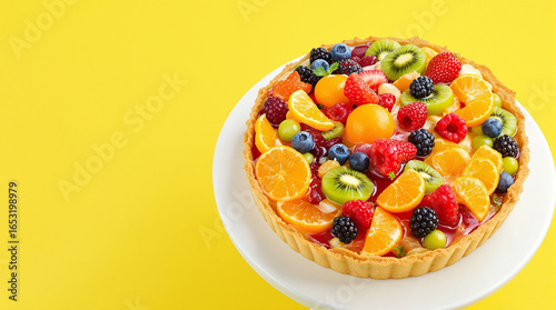 Delicious Fresh Fruit Tart with Mixed Berries and Citrus on White Plate Against Bright Yellow Background for Bakery Food Menu Design