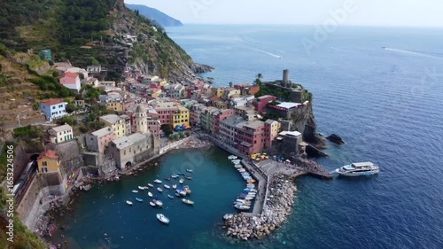 Aerial view of Vernazza, one of the five villages of Cinque Terre, showcases its vibrant architecture and picturesque harbor with boats docked along the shore