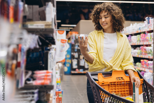Fotografie Woman Choosing Toothpaste in Supermarket While Grocery Shopping