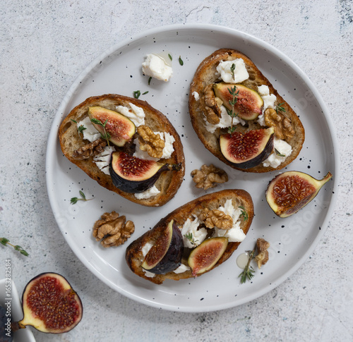 Top View of Fig and Goat Cheese Toasts on White Plate with Figs and Gray Background