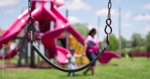 Empty Swing in park with mother and daughter walking by 4k