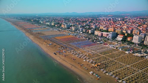 Aerial view of large equipped sandy beaches. Umbrellas and sun loungers for vacationers by the sea. Vacation on the Adriatic Sea. Ferris wheel. Traveling on Europe. Vacation in Italy Rimini 21.07.2025
