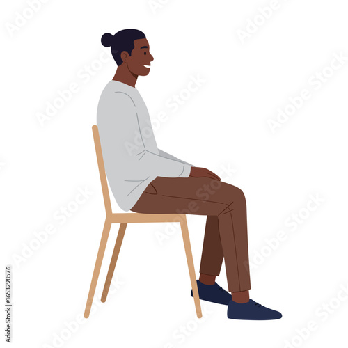 A dark skinned man sitting on a wooden chair with a happy expression