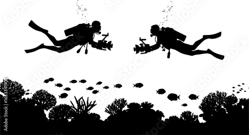Silhouette of two scuba divers with cameras swimming underwater near coral and fish in the ocean water
