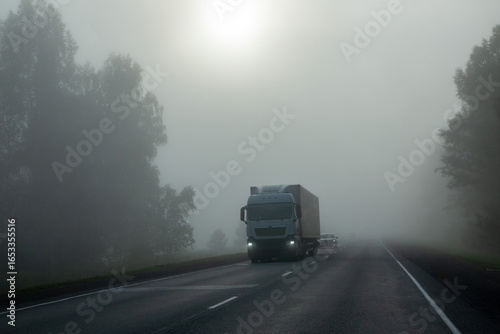 A truck is driving along a country highway in heavy fog.