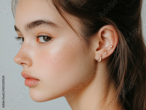 A macro shot of a helix piercing featuring a constellation-inspired design, with tiny star and moon charms. 
